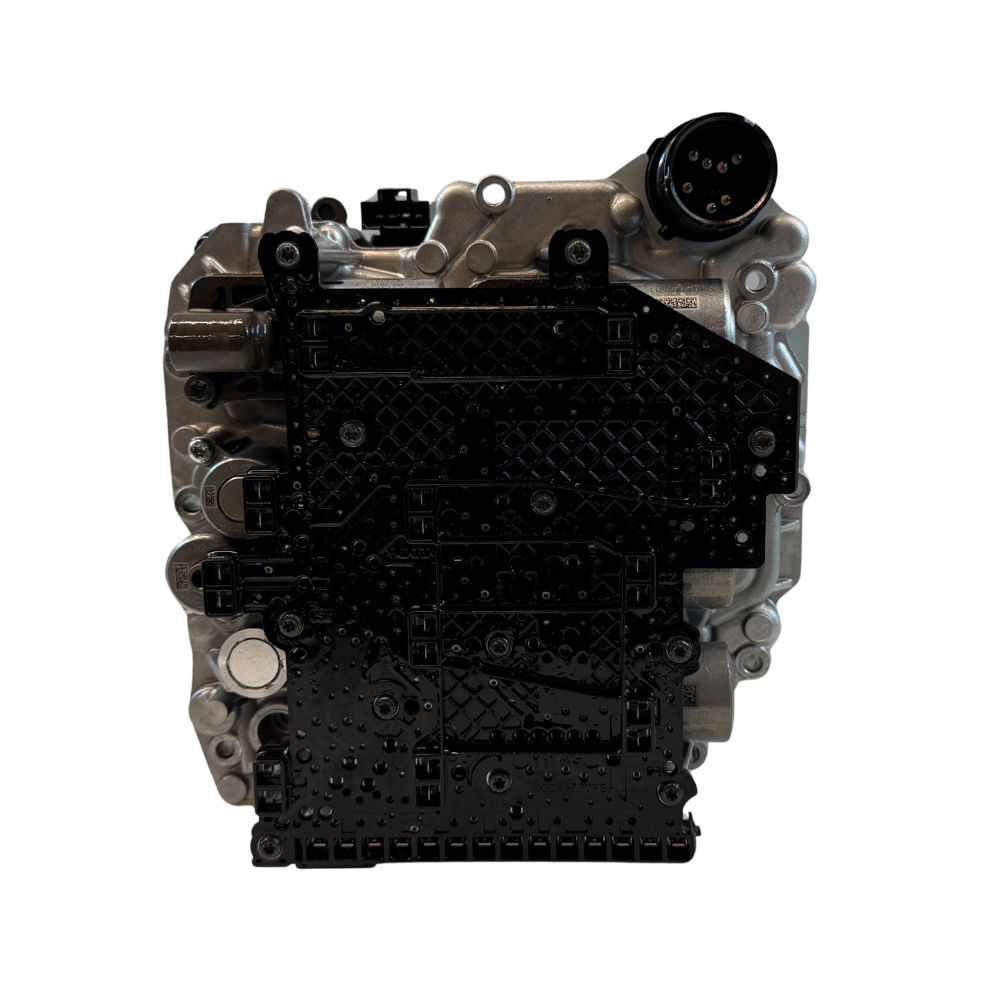 Side profile of a 0BH DQ500 mechatronic unit photographed on a workshop surface